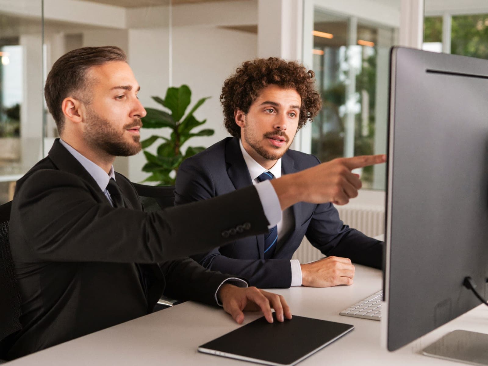 Two colleagues discussing page performance at a monitor