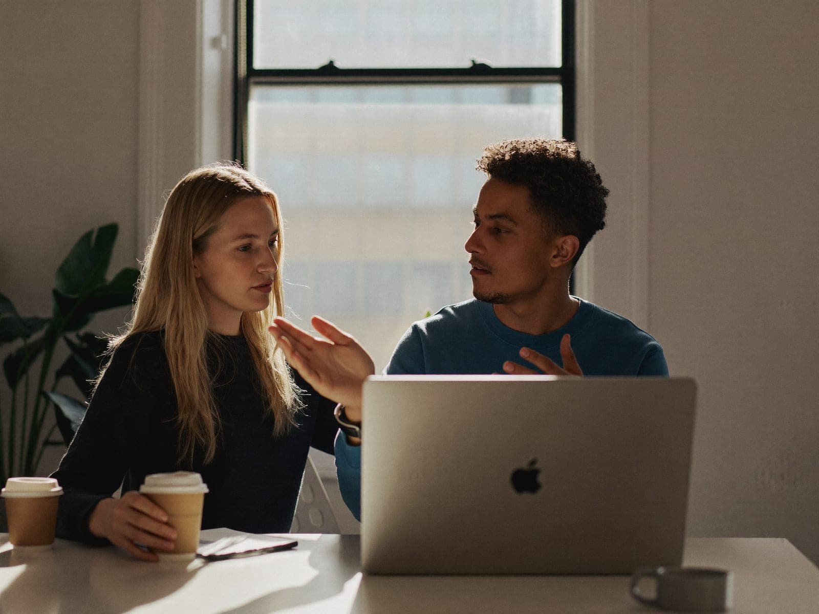 Two colleagues talking through a process at a desk