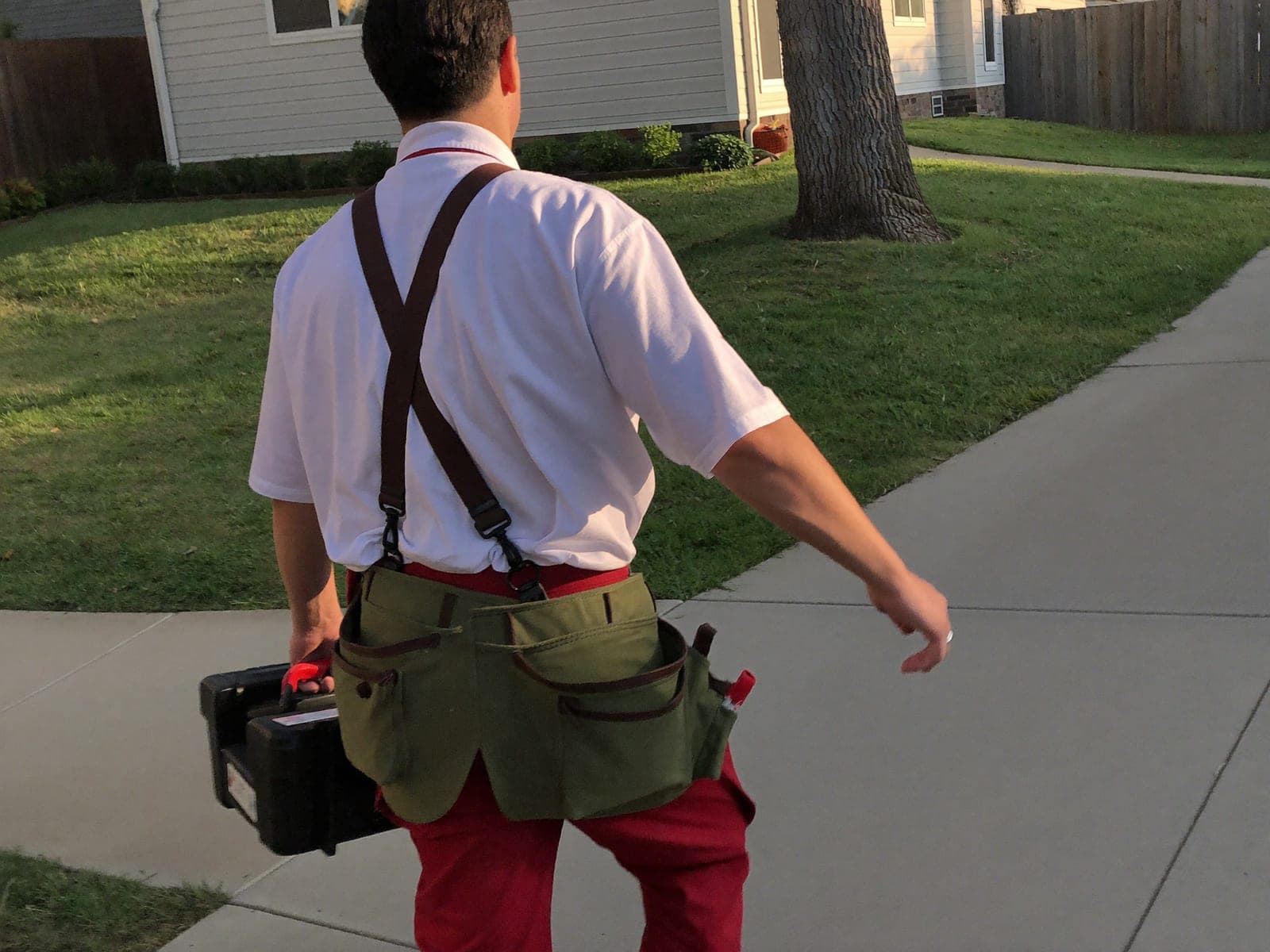 Tradesperson carrying a toolbox up a residential driveway