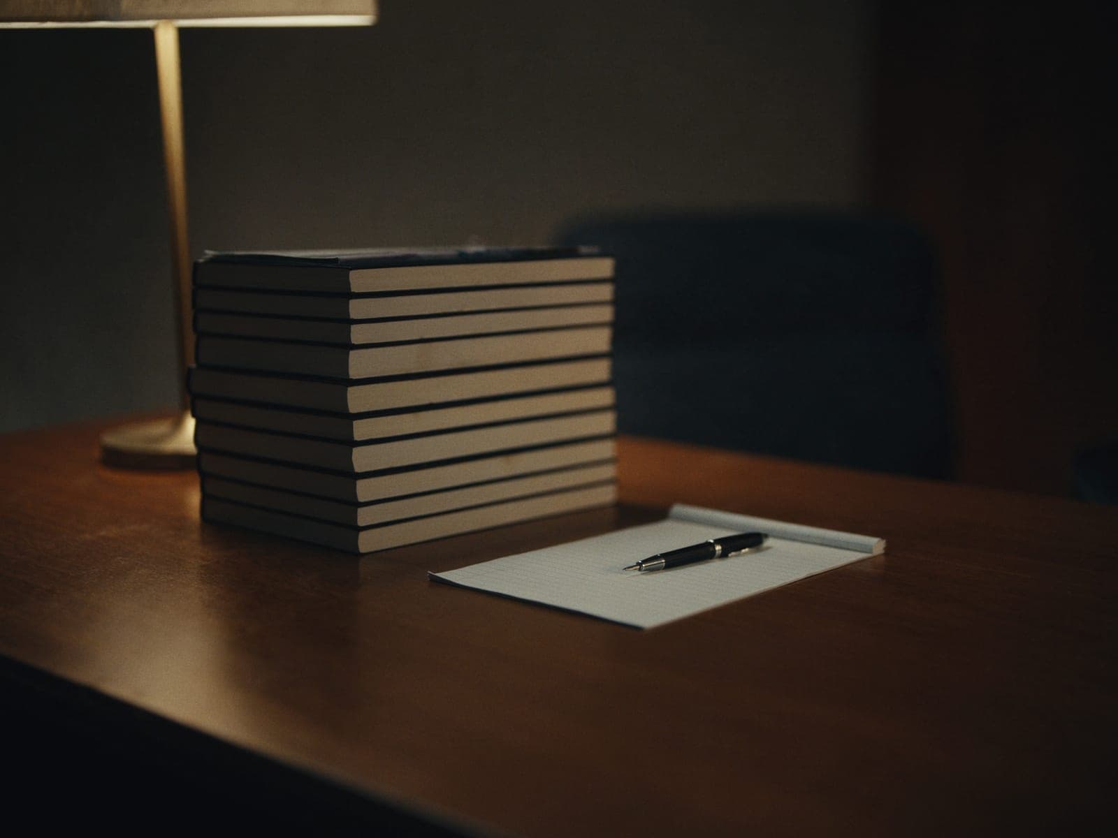 Books, a legal pad and a pen on a polished desk