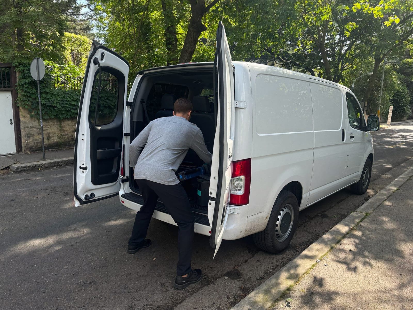 Tradesperson loading tools into a work van on a residential street