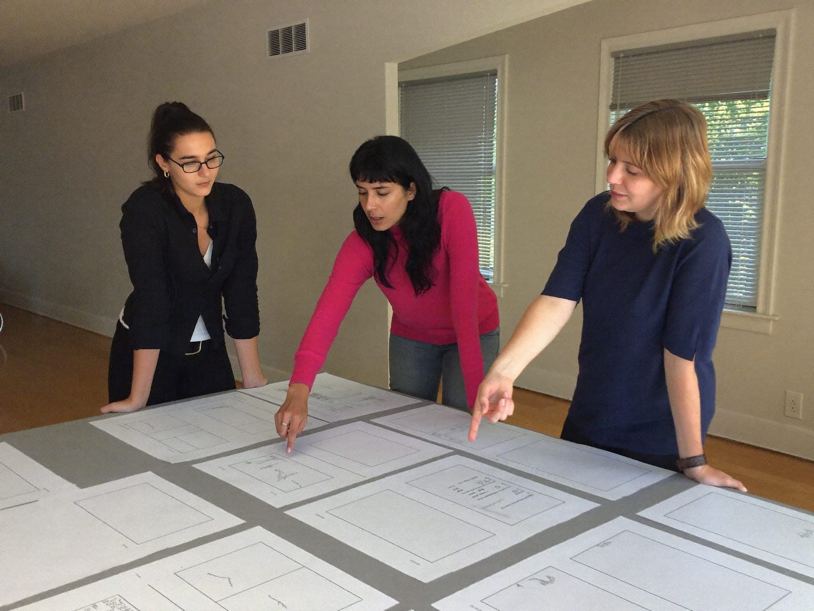 Team reviewing printed page layouts spread across a table
